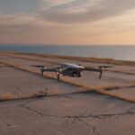 Drone zweeft boven de landingsbaan van een verlaten vliegbasis aan zee